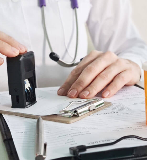 A close-up of a doctor's hands stamping a medical cannabis prescription