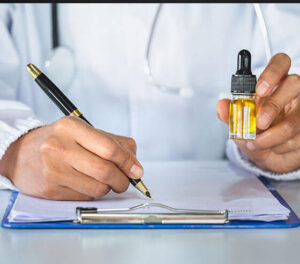 Close-up of a doctor holding a CBD oil while writing a medical cannabis prescription for performance health therapy.